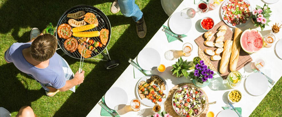 Große Tafel mit Porzellan und Menschen am Grill